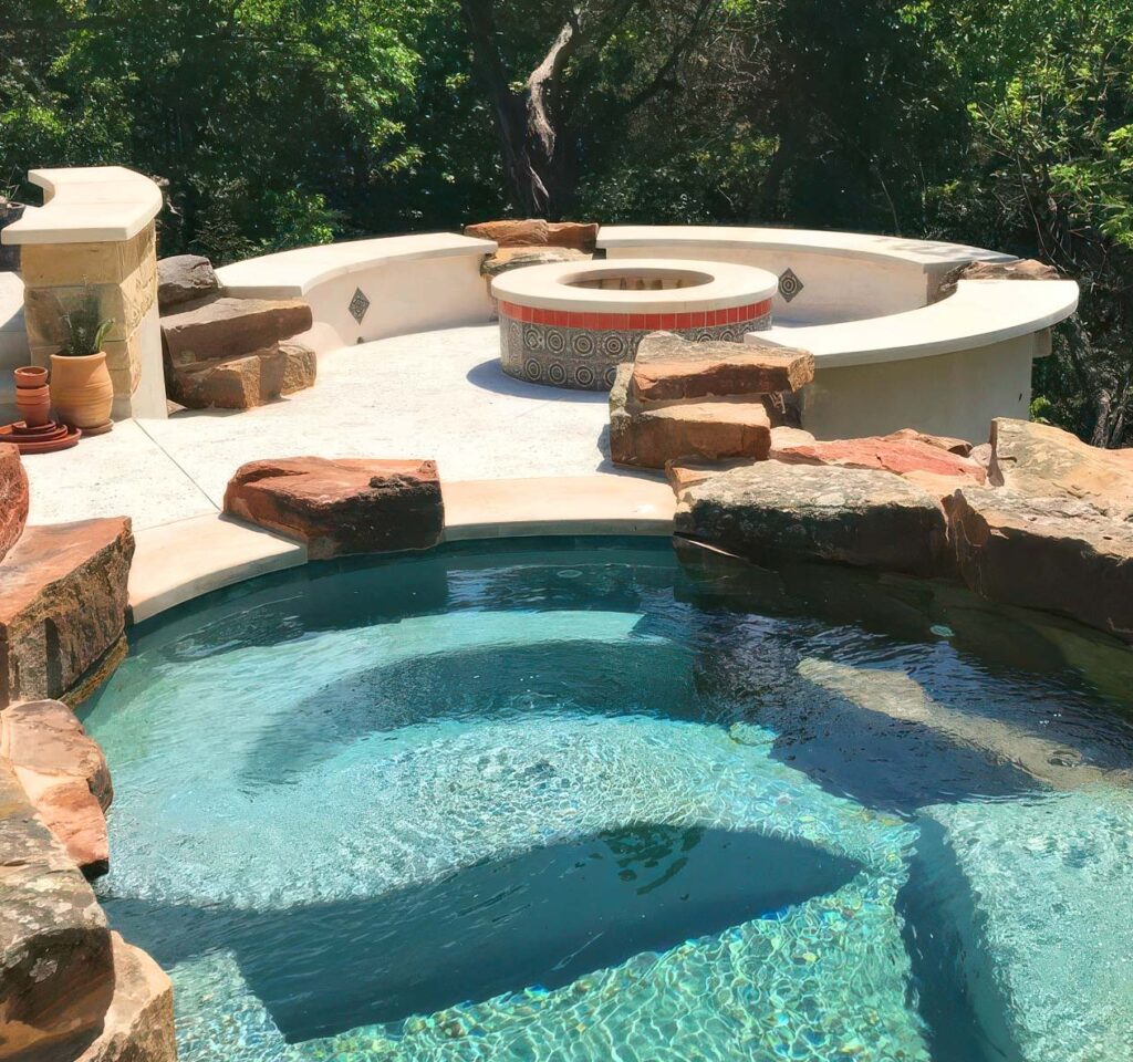 Highly custom designed pool made with natural stone. Adjacent is a spa and fire pit on a patio. All overlooking a scenic dropoff on a truly unique property in Texas.
