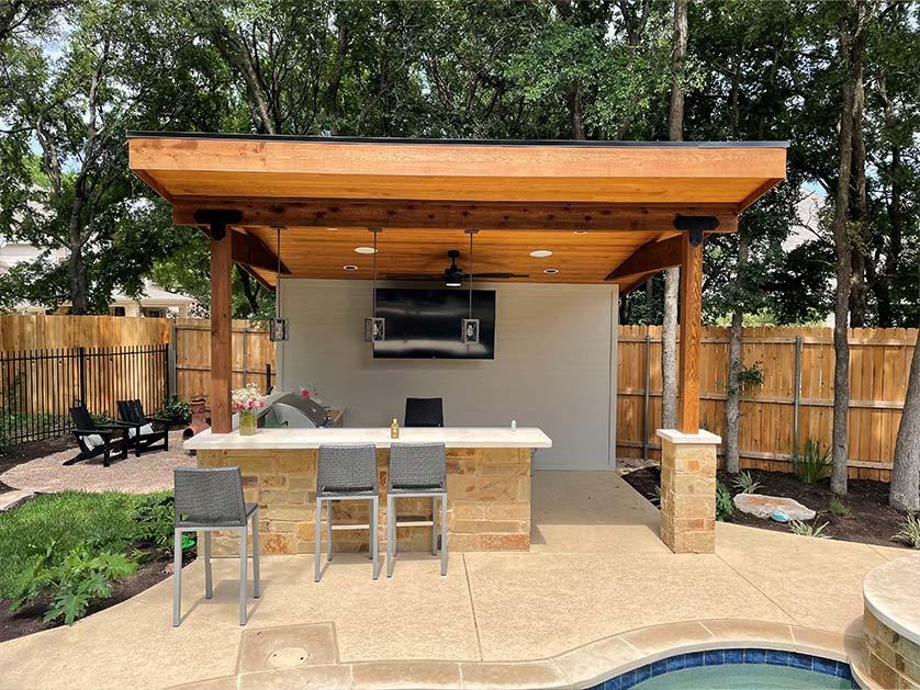 Outdoor bar area covered with pergola and outfitted with a full kitchen next to the pool. Perfect for enjoying a day at the pool without leaving the house.