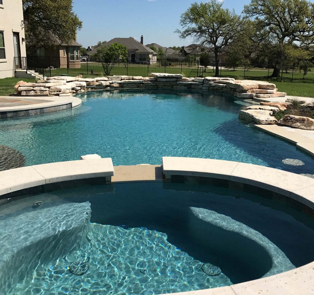 Remodeling job on a pool illustrating new natural stone borders, concrete dividers, and water features that were installed.